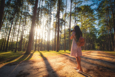 Woman standing by trees in forest