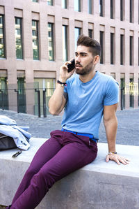 Young man using mobile phone while sitting on street