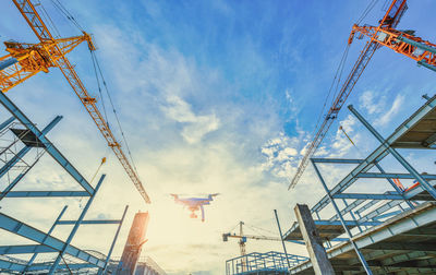 Low angle view of cranes against sky