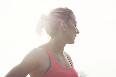 Low angle view of confident athlete looking away while standing against sky