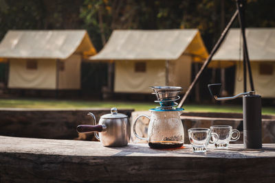 Coffee maker is placed on top of wooden chair in camping area.