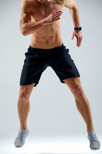 Low section of man exercising against white background