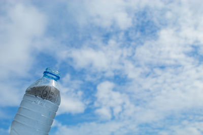 Low angle view of glass bottle against blue sky