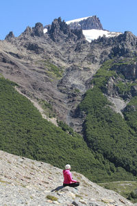 Rear view of man sitting on mountain