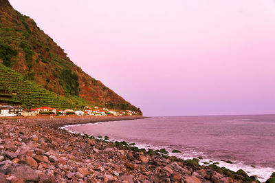 Scenic view of mountain by sea against sky during sunset