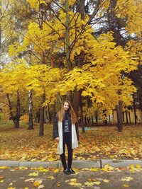 Full length of woman standing in park during autumn