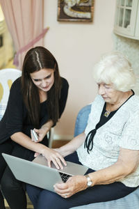 Grandmother and granddaughter using laptop together at home