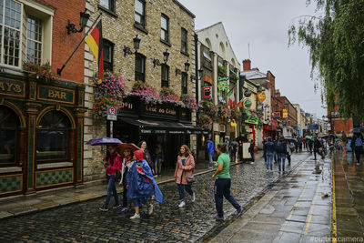 People walking on wet street in city during rainy season