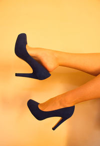 Low section of woman against yellow background