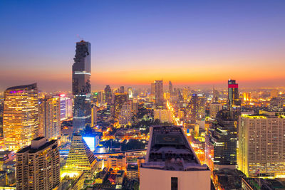 Illuminated cityscape against sky during sunset