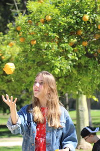 Teenage girl catching orange at orchard