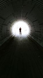 Silhouette man walking in tunnel