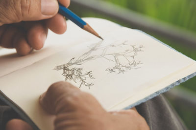 Cropped image of mature man drawing on book