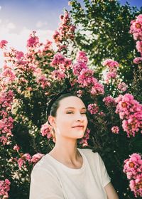 Portrait of woman by pink flowering plants at park