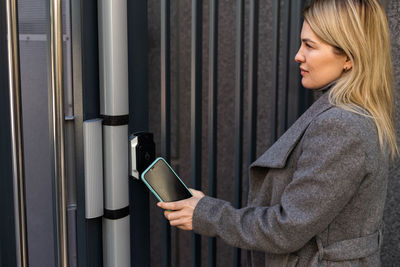 Woman locking smartlock on the entrance door using a smart phone. concept of using smart electronic