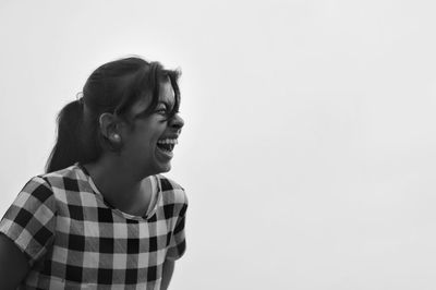 Teenage girl laughing against clear sky