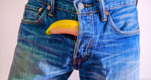 Close-up midsection of man with banana in jeans pant