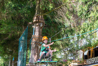 Adventure climbing high wire park - people on course in mountain helmet and safety equipment