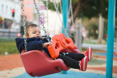 Cute girl sitting on swing at park