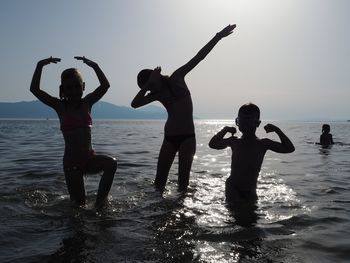 Friends standing on beach against clear sky