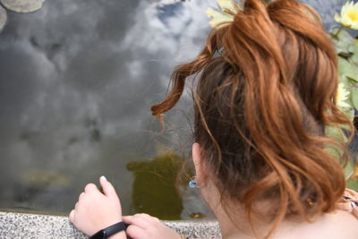 Young red-haired girl peering into the pond after a walk
