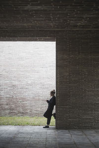 Side view of woman standing by wall