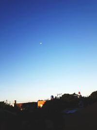 Silhouette trees against clear blue sky at night