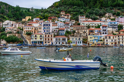 Sailboats moored on sea by buildings in city