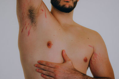 Midsection of shirtless man standing against white background