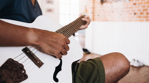 Midsection of man playing guitar