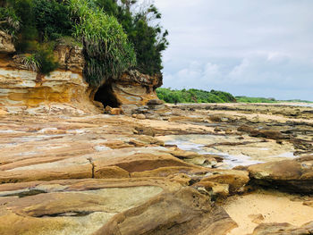 Rock formations on beach against sky