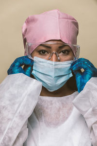 Portrait of doctor wearing mask against blue background