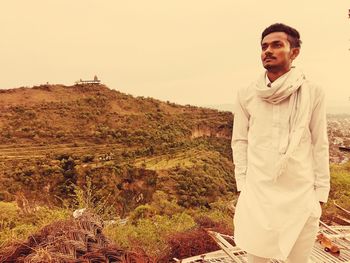 Portrait of man standing on landscape against sky