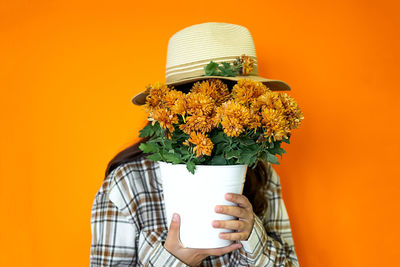 Rear view of woman wearing hat against yellow background