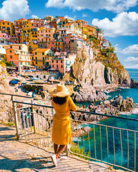 Rear view of woman standing by sea against sky