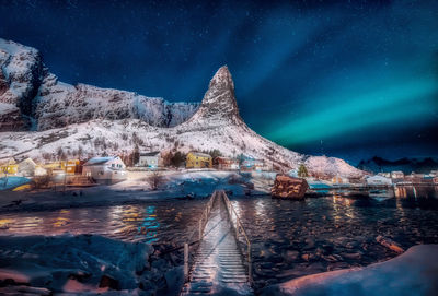 Scenic view of lake by illuminated mountain against sky at night