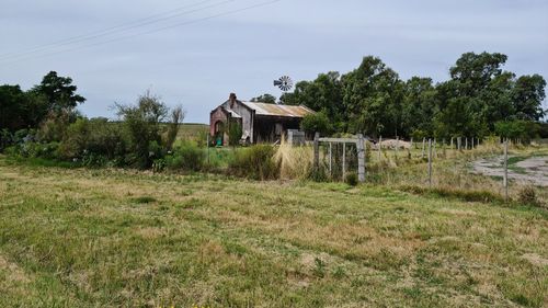 House on field by trees against sky