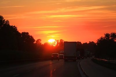 Cars on road against sky during sunset