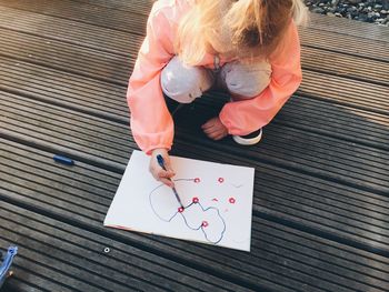 High angle view of baby girl drawing while crouching outdoors