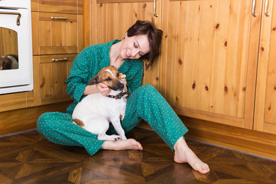 Smiling woman playing with puppy at home