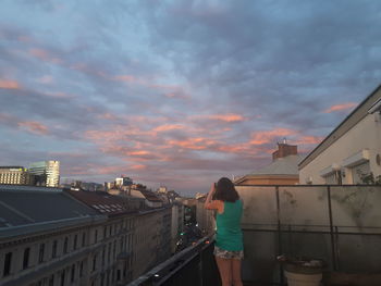 Rear view of woman standing on city against sky