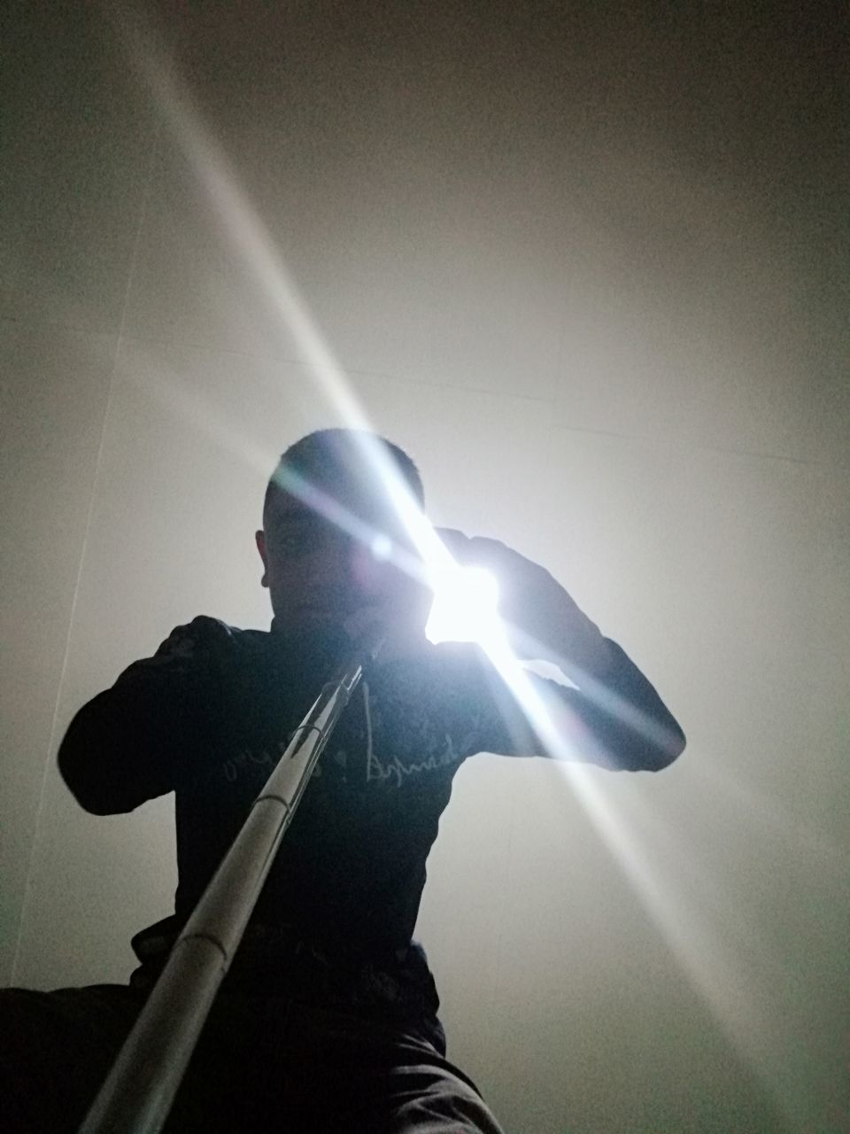 LOW ANGLE VIEW OF MAN WITH ILLUMINATED LIGHTING EQUIPMENT