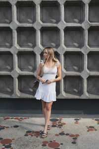 Full length of woman standing against wall