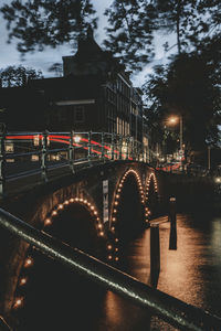 Illuminated bridge over river in city