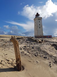 Lighthouse on beach with shell against sky