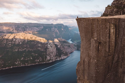 Man sitting on edge of cliff at fjords in prekeistolen norway