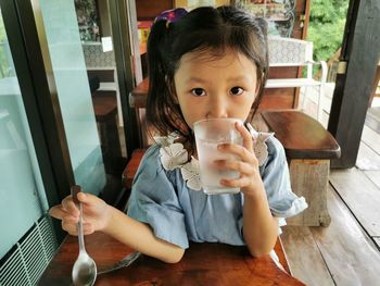 Portrait of cute girl drinking glass on table