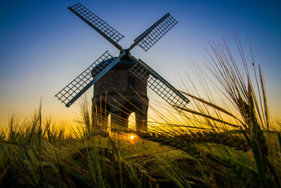 Traditional windmill on field against sky at sunset