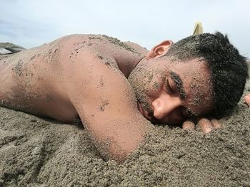 Portrait of young woman lying on sand