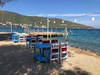 Chairs and tables at beach against blue sky